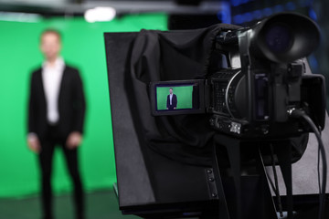 Presenter working in studio, focus on video camera screen