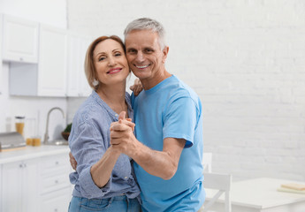 Happy senior couple dancing together in kitchen
