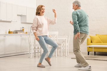 Happy senior couple dancing together in kitchen