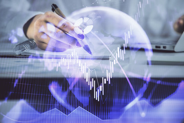 Double exposure of woman's hands making notes with forex graph hologram. Concept technical analysis.