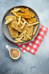 Round grey plate with fish and chips, above view on a light-blue stone background, vertical shot