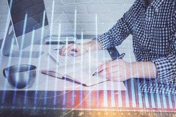 Double exposure of stock market chart with man working on computer on background. Concept of financial analysis.