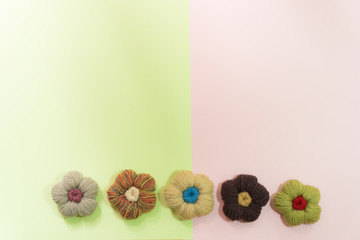 Flat lay of many Knitting yarn in a flower shape on pastel pink and green background with copy space for text or advertisement