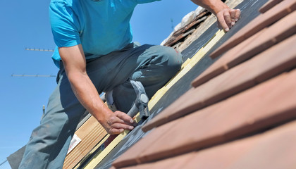 Fototapeta na wymiar close on a worker holding a hammer and renoving a roof of a house