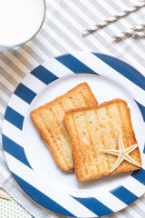Breakfast toast, orange juice, water for children in the marine theme, creative with shells on a blue background