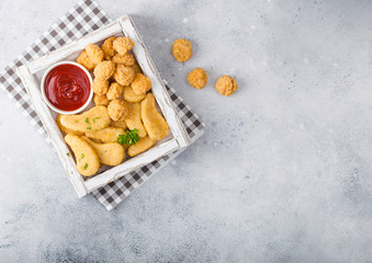 Buttered chicken nuggets and popcorn bites in white vintage wooden box with ketchup on light background. Top view. Space for text