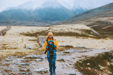 Fototapeta premium Mother with baby carrier hiking travel family healthy lifestyle woman and child active vacations outdoor in Norway mountain trail Rondane park.