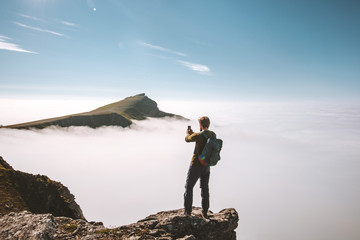 Man blogger with smartphone on mountain cliff travel vacations adventure content creator influencer lifestyle outdoor over clouds landscape in Norway.