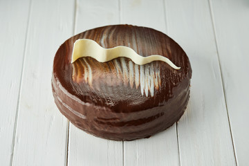 Dark chocolate vegan cake with candies and nuts on wooden background