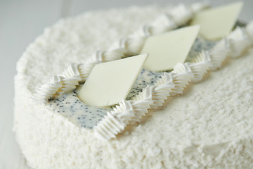 Birthday cake with white chocolate, butter cream and poppy seed biscuit on wooden background