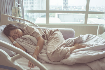 Asian woman get sick from influenza have admit to hospital with saline intravenous (iv) in-line hand pressure. Patient sleeping rest in the patient's bed.