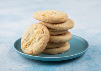 White chocolate biscuit cookies on blue ceramic plate on blue kitchen table background.