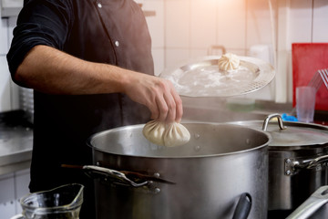 Chef coocking georgian khinkali or japanese wonton. Traditional meal of dough and meat. National cuisine, cooking process. Restaurant kitchen.