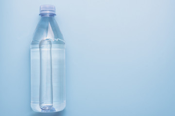 Plastic water bottle on blue background with copyspace, top view
