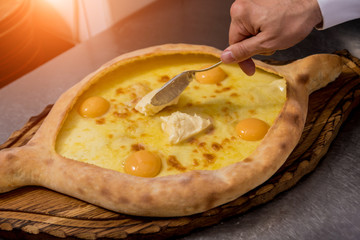 Chef cooking khachapuri with cheese and egg. Georgian national cuisine. Restaurant.