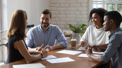 Smiling diverse colleagues discussing project strategy at briefing