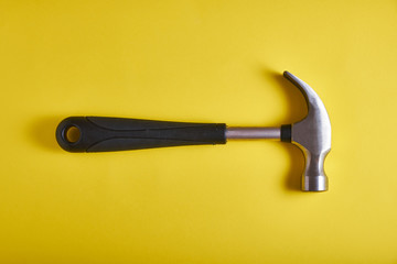 Metal hammer with a plastic handle on a yellow background, top view