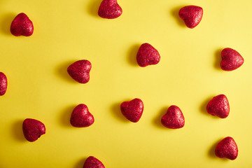 Fototapeta na wymiar Red little hearts on a yellow background