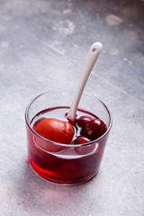 Glass of pickled apricot and cherry with spoon. Easy homemade fruit compote