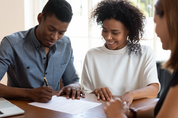 Happy African American couple signing contract, making deal