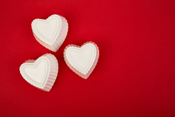 White ceramic hearts on red background. Flat lay composition. Romantic, St Valentines Day concept. Love. Copy space.