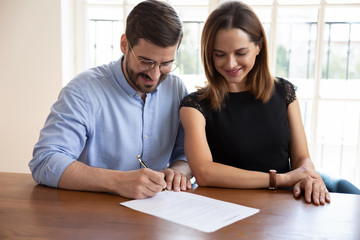 Fototapeta premium Happy married couple signing contract, making legal deal