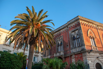 Palme vor terracotta farbenem Haus in Syracusa, Sizilien
