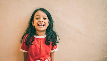 Portrait of an Asian little girl with long wavy hair and wearing a brick red shirt. Cute expression of 7 year old girl. Asian child.