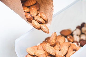 Pour almonds and hazelnuts into one bowl to create an assortment of nuts for a balanced diet.