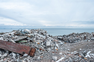 Sea shore in the mountains of building debris. Concrete ruins on the site of residential slums.