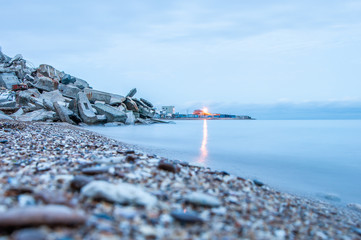 Scenery of a seashore shot for a long exposure. Blurred water. The shore is in ruins from the premises.