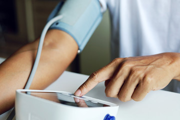 Close-up man measure pressure by yourself in room.