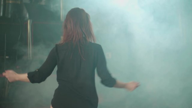 Female person dancing in the smoke 4K. Long shot tracking female person in focus dancing in front of a locomotive in smoke.