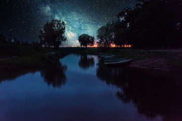 Starry Night over a Still Lake in Latvia with Fishing Boats