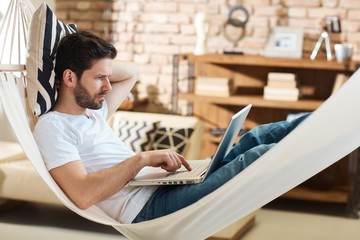 Man using laptop in hammock