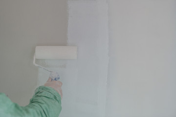 Roller painting white wall, ceiling with white paint