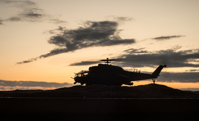 Naklejka na ściany i meble Silhouette of military helicopter ready to fly from conflict zone. Decorated night footage with helicopter starting in desert with foggy toned backlit. Selective focus.
