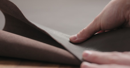 man hand checking brown leather piece closeup