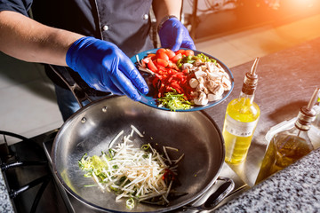 Chef cooking pasta with vegetables in pan. Italian style cuisine. Restaurant.