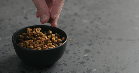 man hand take dried seaberry from black bowl on terrazzo countertop