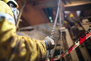 Close up picture of rigger wearing helmet safety glass using hand commencing pulling a heavy duty...