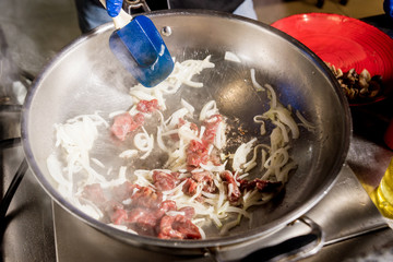 Chef cooking pasta with meat in pan. Italian style cuisine. Restaurant.