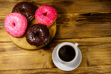 Cup of coffee and tasty donuts on a wooden table. Top view