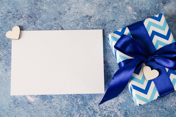 Greeting card for Father's Day or Birthday. Gift box with blank white paper on blue background.