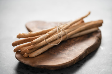 bunch of handmade wholegrain grissini tied with rope on olive board