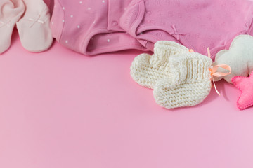 Pink background with clothes, socks and toys for a newborn girl. 