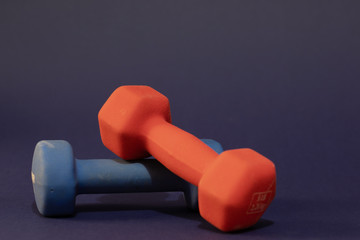 Hand weights, red and blue, each of Five pounds, close-up and isolated on dark blue background