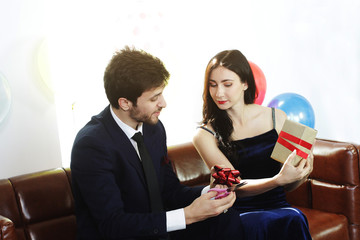 Sweet couple Love smile and spending Romantic christmas time and celebrating new year eve, birthday, and valentine on Brown Sofa decoration with colorful balloon and Gift Boxes in Living room at home