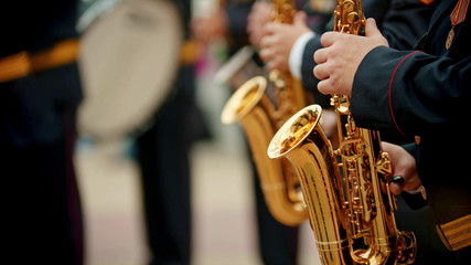 Obraz premium A man plays the saxophone. jazz musician in a white shirt plays the trumpet. closeup shot of a gold saxophone held by a musician