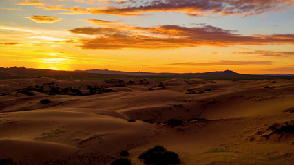 Beautiful sunset in a deserted desert, covering with orange light all around